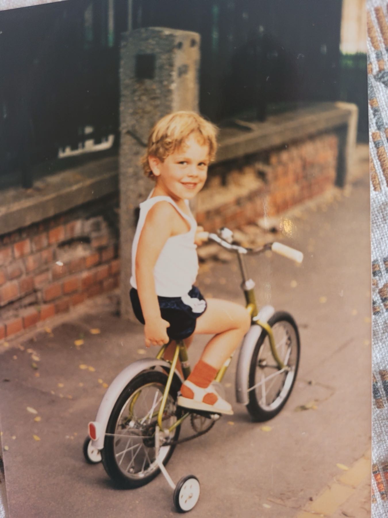 Adam as a boy, on training wheels, on a cobblestone street in Budapest.