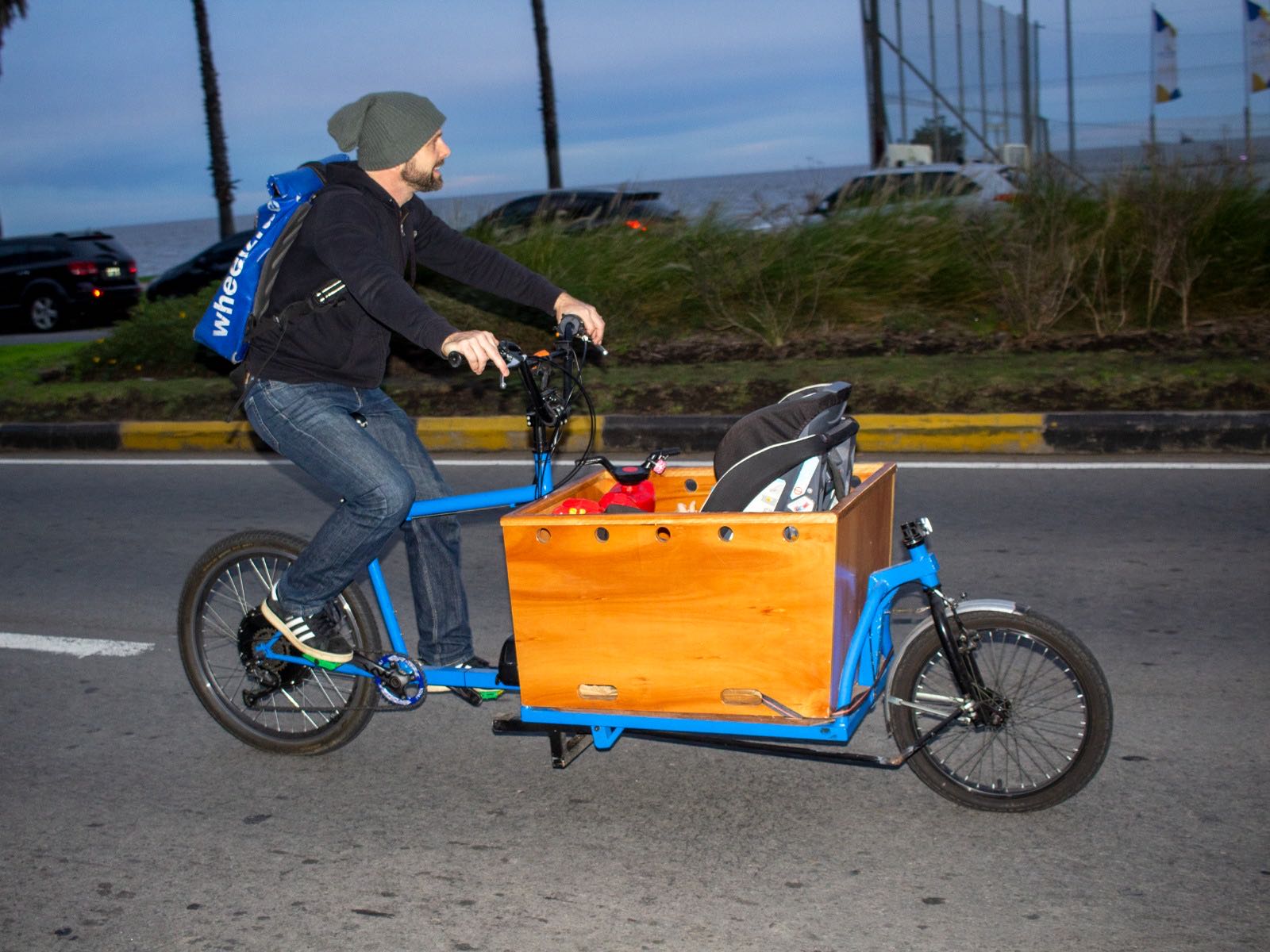 Adam riding a cargo bike along the rambla at dusk.
