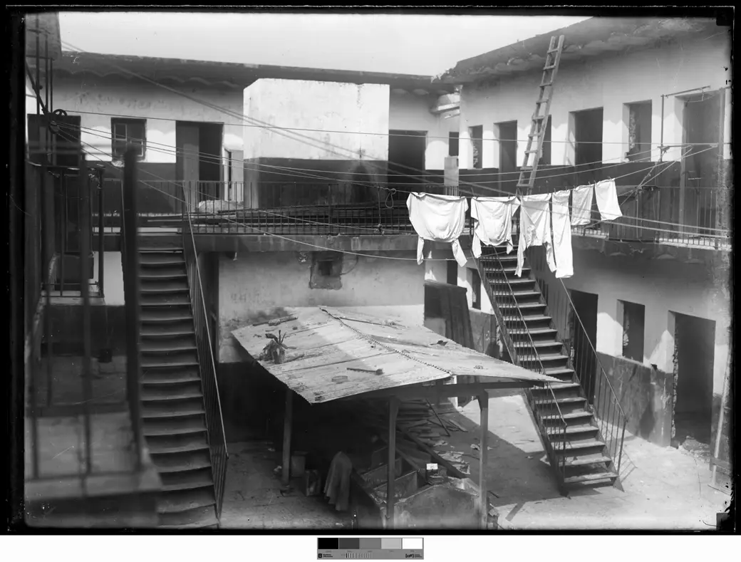 Undated historical photo: the interior courtyard of the Medio Mundo tenement, with two symmetrical iron staircases and laundry lines strung between the upper-floor galleries.