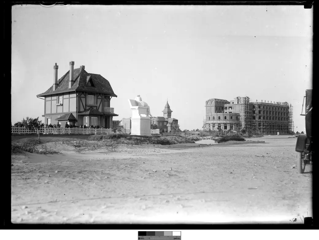 Historical photo, 1917-1920: the Hotel Carrasco under construction among the dunes, with one finished neighbouring chalet and open sand around it.