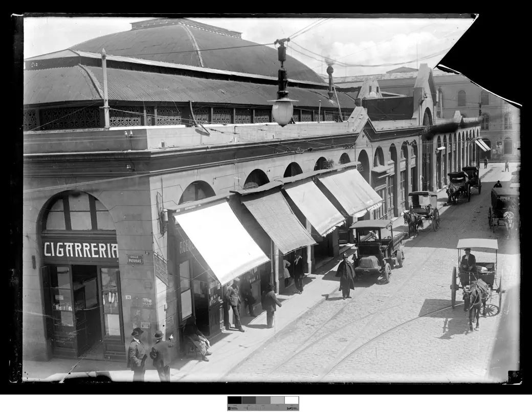 Historical photo, circa 1915: the corner of Piedras and Pérez Castellano, with the Mercado del Puerto's iron-and-glass arcade, awnings, a tobacconist and a horse cart.