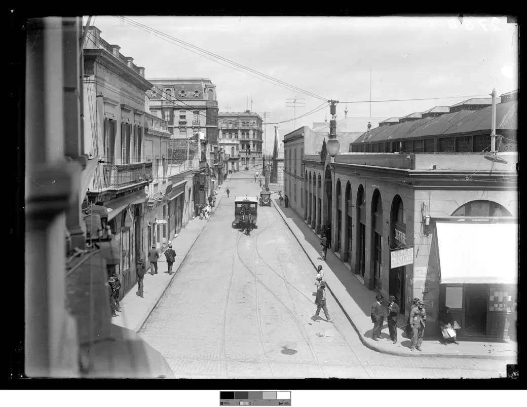 Historical photo, circa 1920: Calle Piedras with the Mercado del Puerto's façade and a tram line in the foreground.