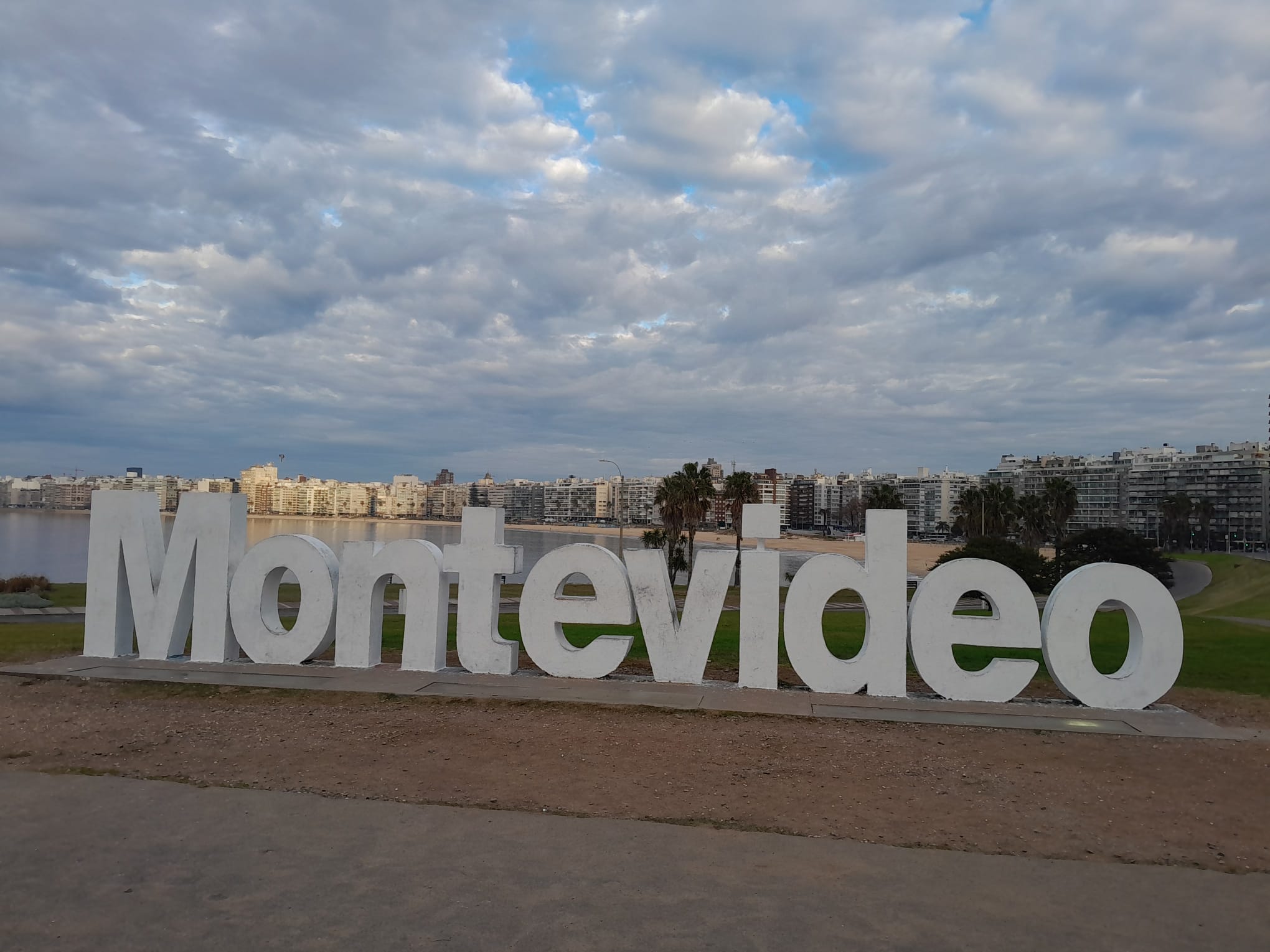 The MONTEVIDEO letters on the Pocitos rambla, with the beach and towers behind.