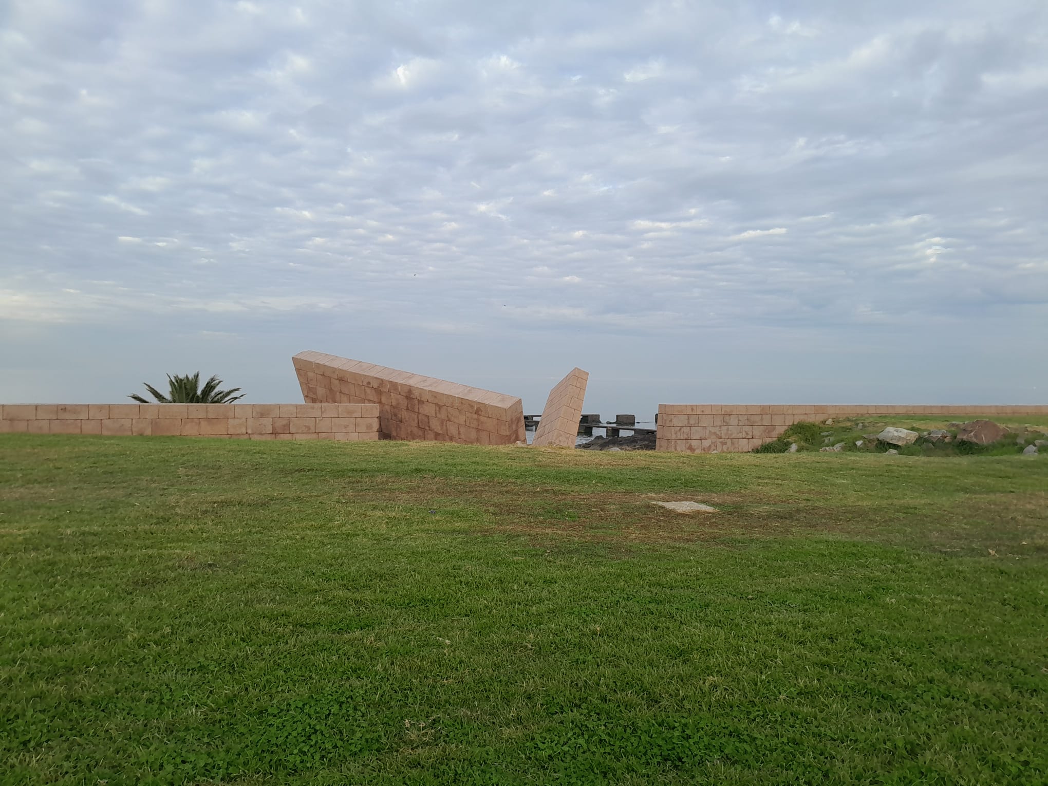 The Holocaust Memorial wall seen from the front, on the lawn that slopes to the river.