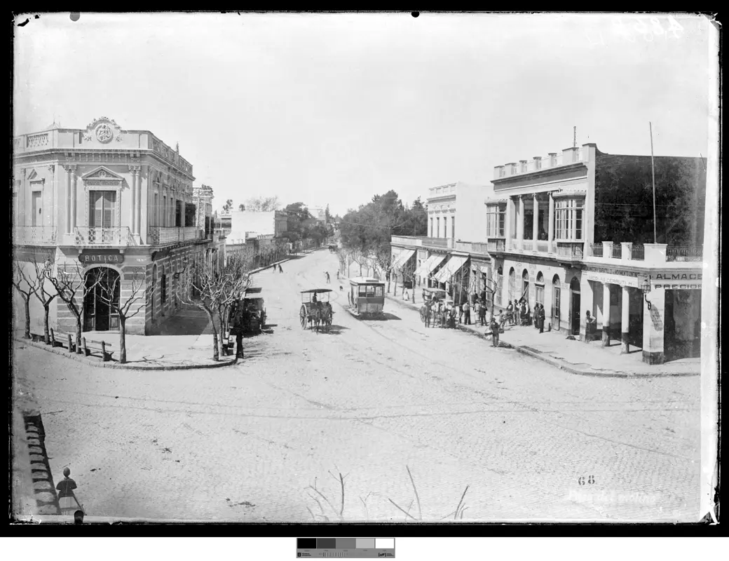 Historical photo, 1908: the intersection of Agraciada and Lucas Obes, with a tram, a horse carriage, a parked automobile, and pedestrians sharing the same roadway.